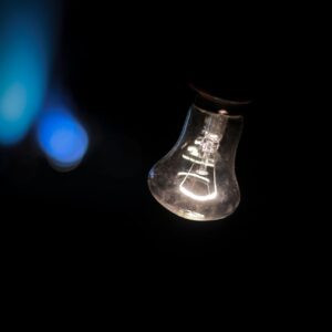 Home Glowing light bulb with bokeh effects in a dark, moody setting.