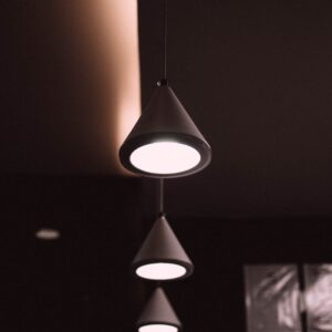 Home Elegant cone-shaped pendant lights creating a modern atmosphere in a dark interior space.