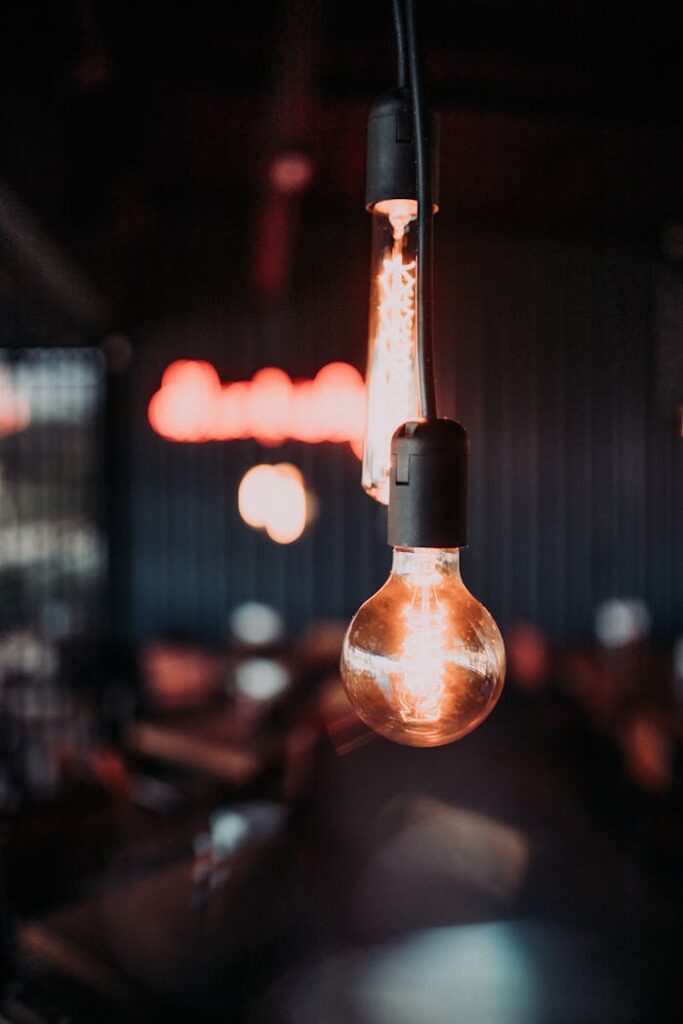 Atmospheric shot of glowing light bulb in a dark room setting.