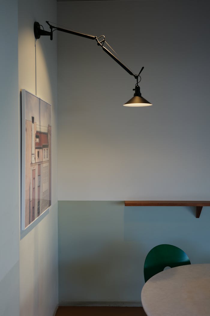Minimalist interior with a spotlight and wall art, casting soft shadows on a neutral wall.