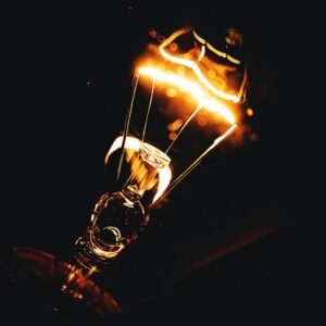 Home Dramatic close-up photo of an illuminated light bulb filament glowing in the dark.